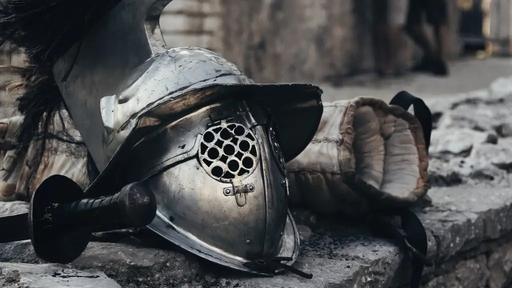 mascara metalica de gladiador junto a una espada y guantes
