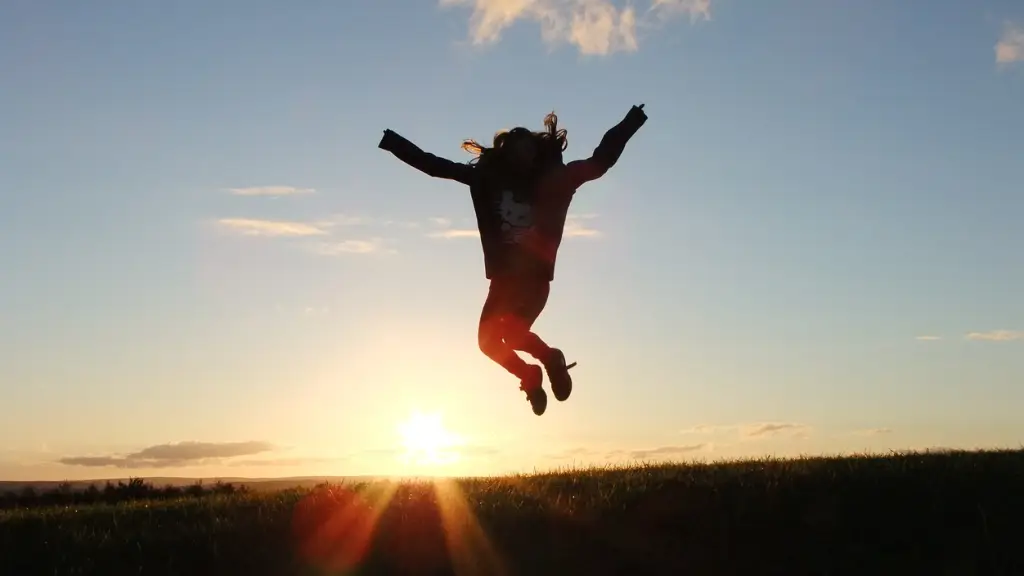 la silueta de una mujer que salta de alegría y victoria con el sol de fondo