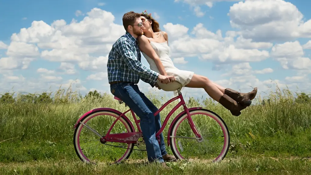 una pareja en bicicleta se da un beso en una tarde soleada en medio del campo