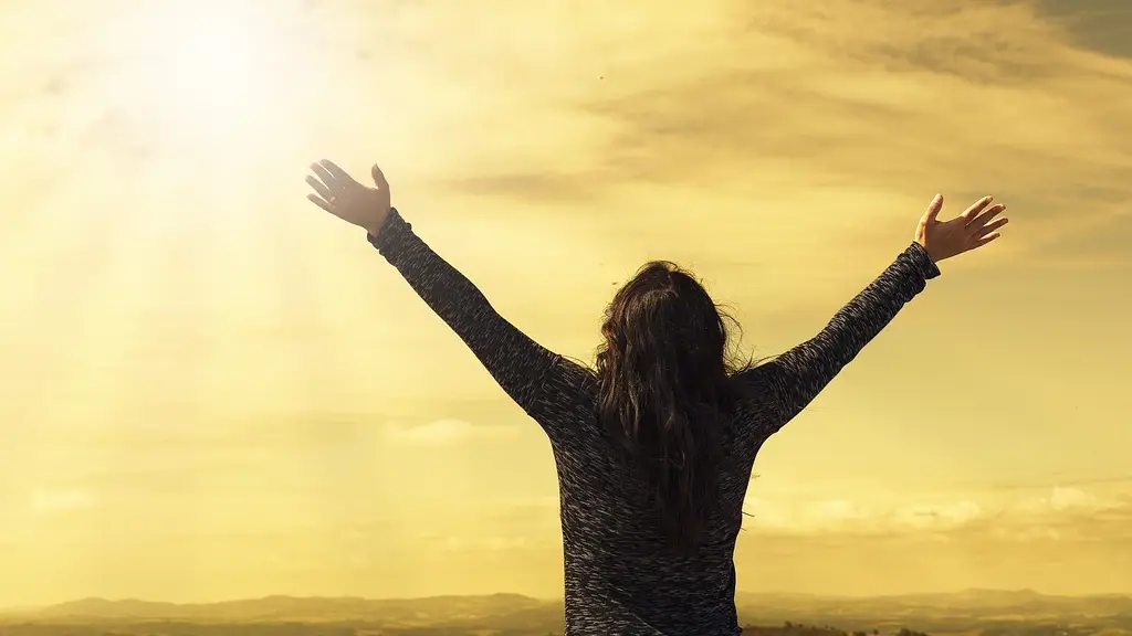 una mujer levantando los brazos y mirando en dirección al sol. Una señal de triunfo y éxito, un emblema de victoria