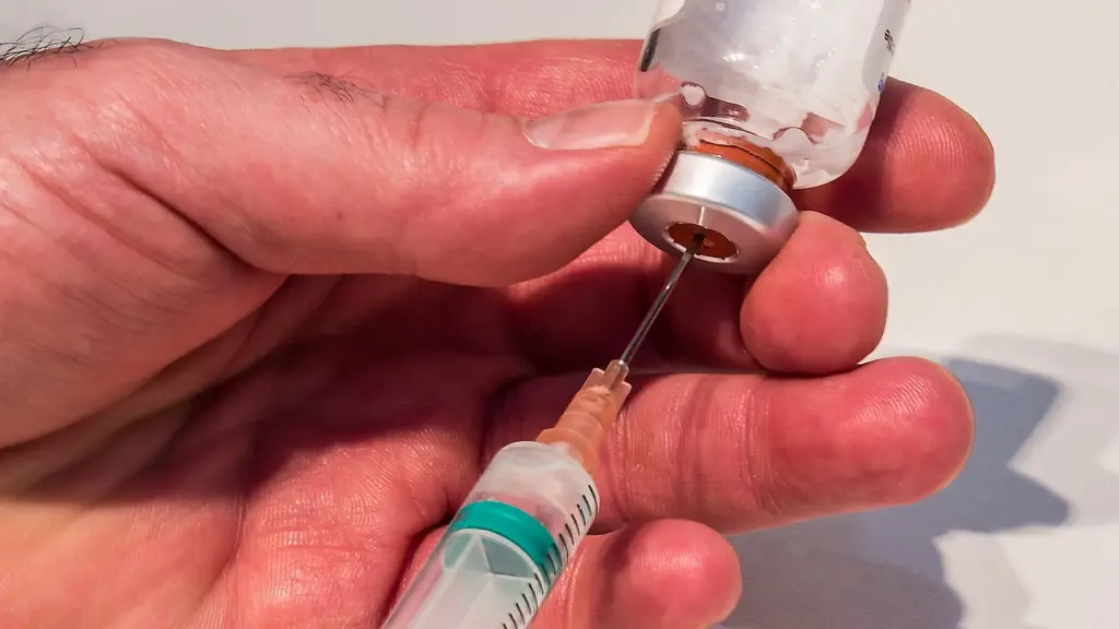 Jeringa extrayendo líquido de una botellita de inyectable