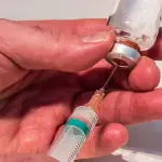 Jeringa extrayendo líquido de una botellita de inyectable